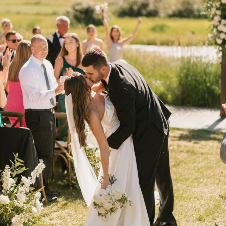 bride and grooming kissing while walking down the aisle